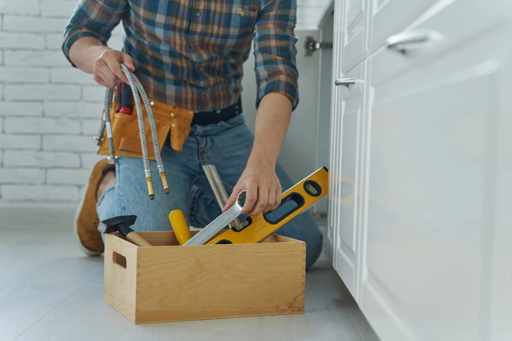 Plumber fixing under the sink in the kitchen